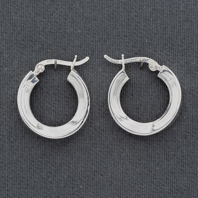 A pair of polished silver hoop earrings with a textured, ribbed outer surface and classic fishhook clasps, displayed on a dark gray textured fabric background.