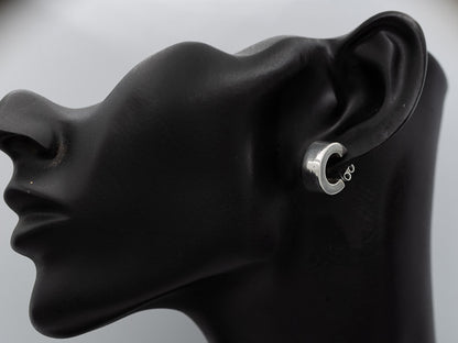 A silver hoop earring with a small infinity symbol on the inner band, shown on a black mannequin head in profile against a light gray background.