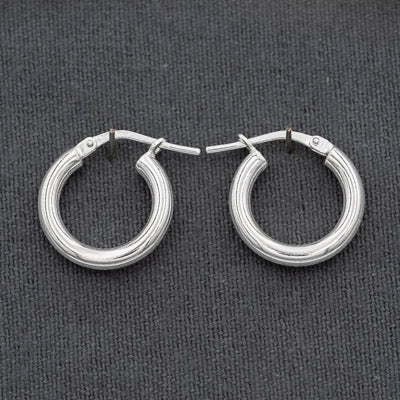 A pair silver hoop earrings with post-back closures, displayed on a dark gray textured fabric background.