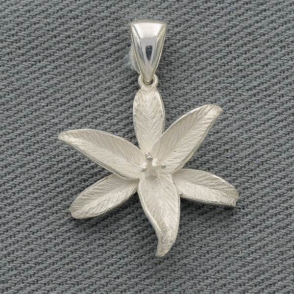 A sterling silver pendant in the shape of a flower with polished petal edges on a textured background.