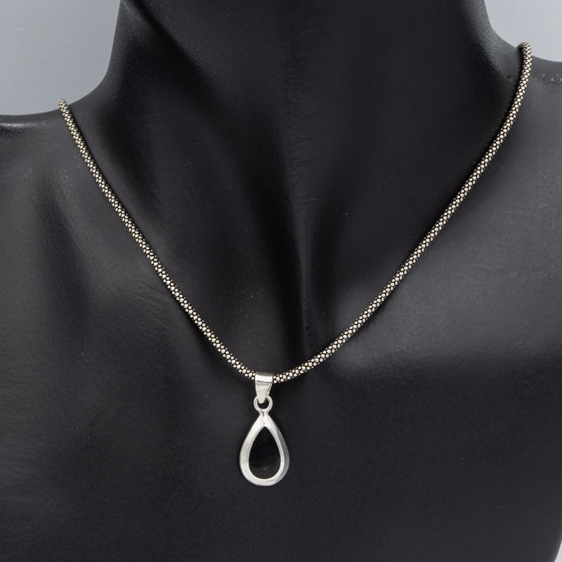 A silver teardrop pendant necklace on a matching silver chain, displayed on a black mannequin bust against a neutral gray background.