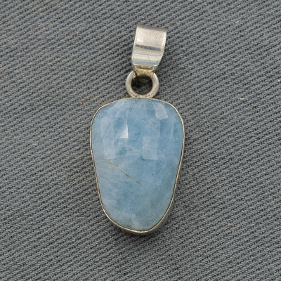 A sterling silver rough aquamarine pendant with a free-form design, displayed against a textured background.