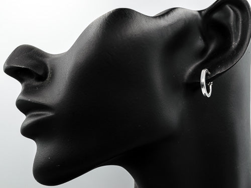 A close-up side profile of a black mannequin head and ear wearing a small silver hoop earring against a light gray background.